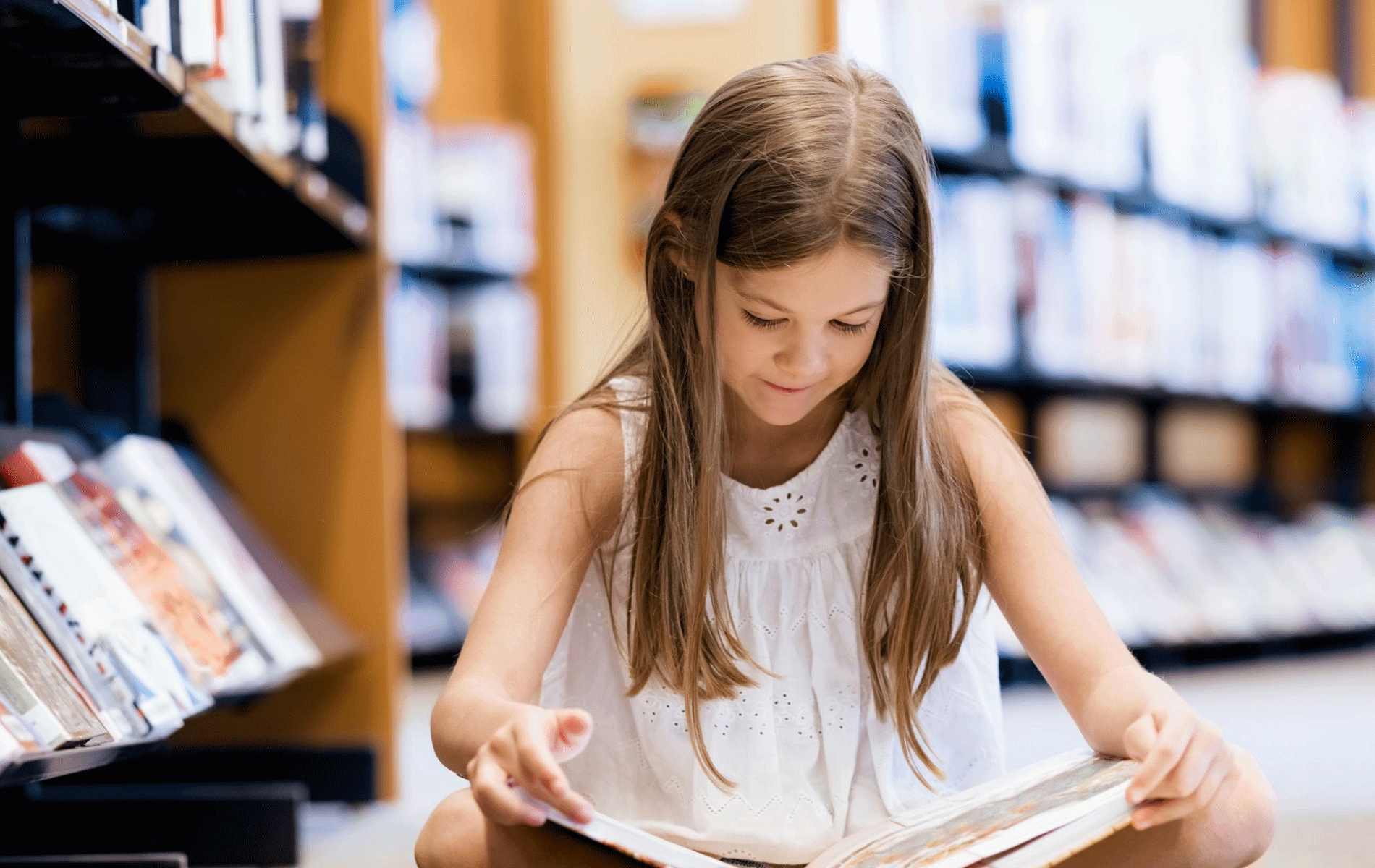 Child reading a book in a library.